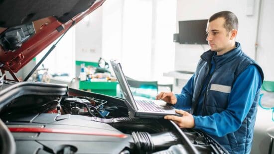 Engineer makes computer diagnostics of the car in autoservice. Vehicle wiring inspection