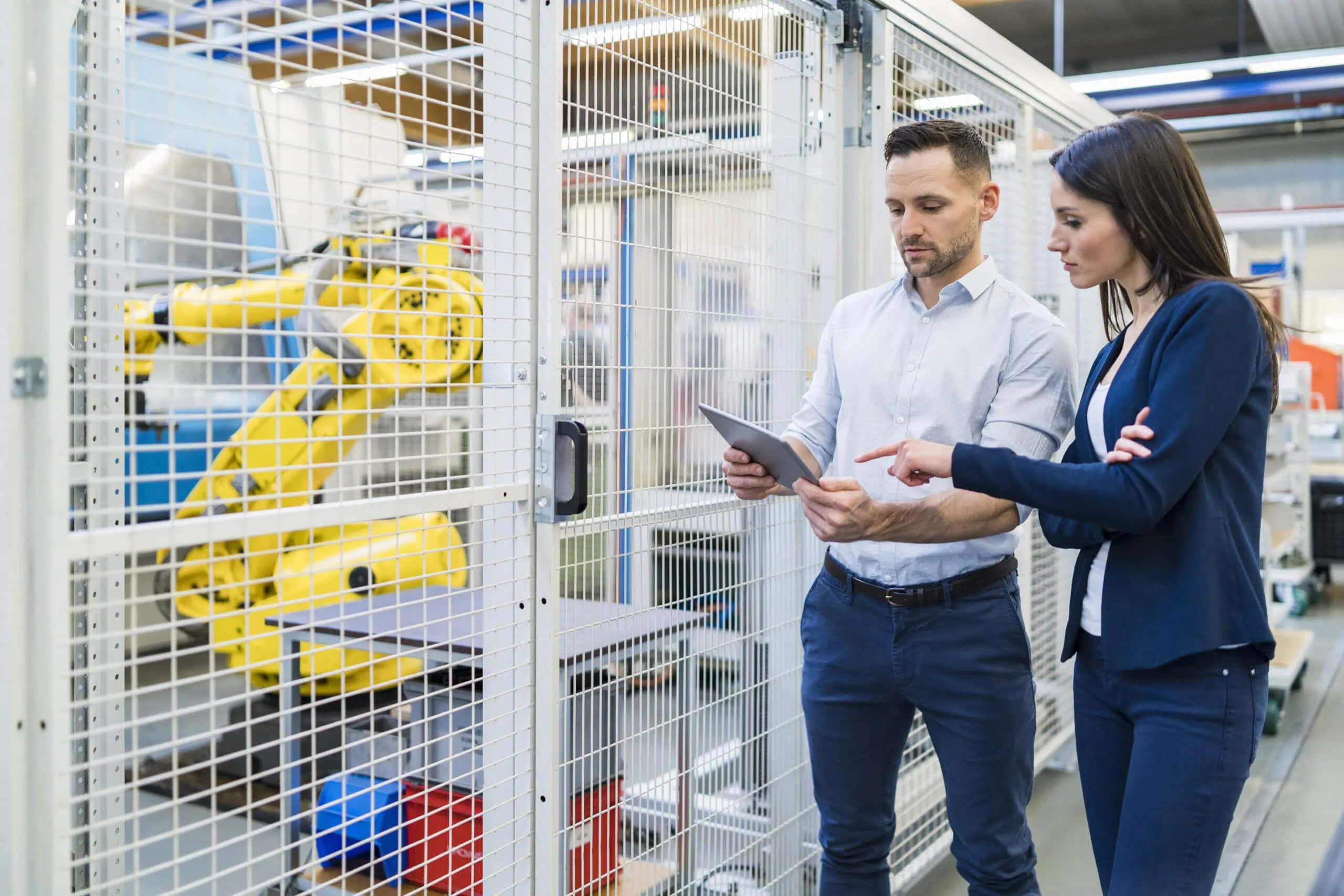 businessman and businesswoman with tablet talking in modern factory